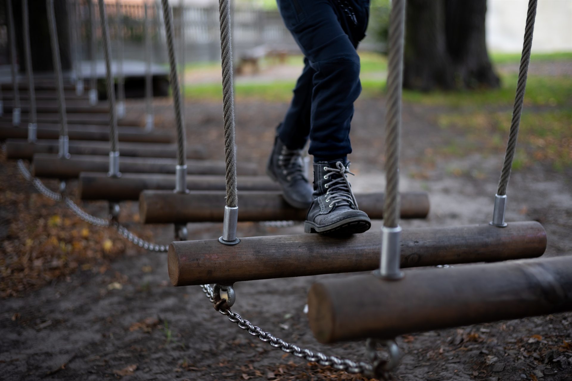Czarne trapery i nogawki na wiszących drewnianych belkach z linami i łańcuchami